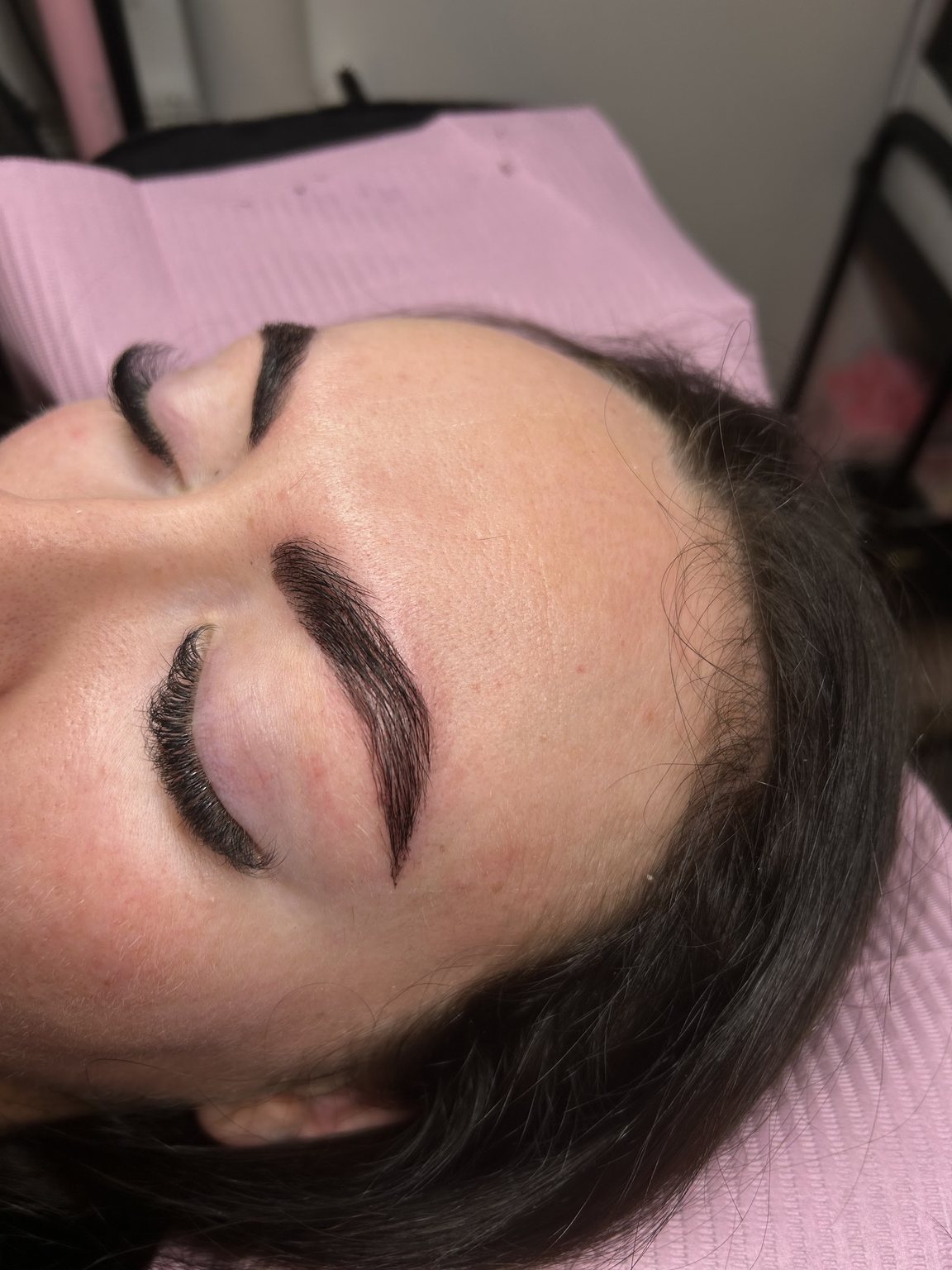 Laminated, tinted brows and a full lash set, eyes closed